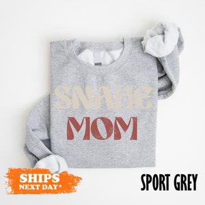 a gray shirt with a white ruffle sleeve and a slogan on it