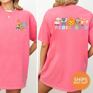 a woman wearing a pink tshirt with cartoon characters on it