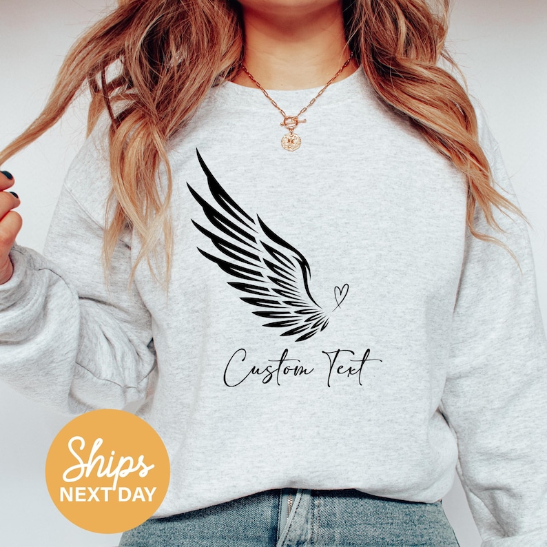 a woman wearing a grey sweatshirt with a black and white bird on it