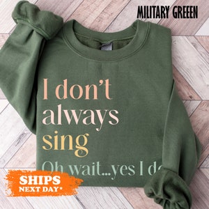 May include: A green sweatshirt with the text "I don't always sing Oh wait...yes I do" printed on it. The text is in pink, yellow, and light blue.