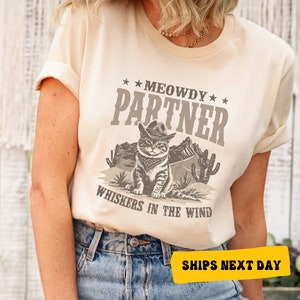 a woman wearing a t - shirt that says meowdy partner whiskeys in