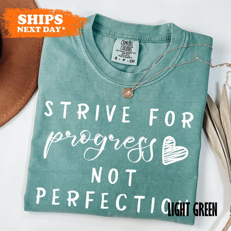 a t - shirt that says, strike for progress not perfection