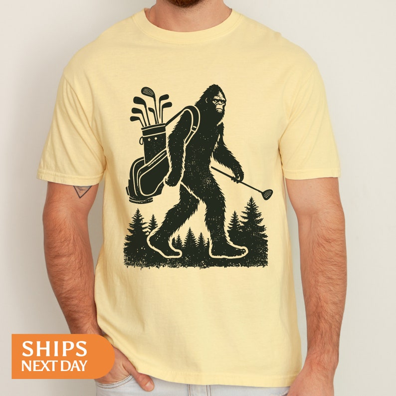 a man wearing a yellow shirt with a bigfoot holding a golf club
