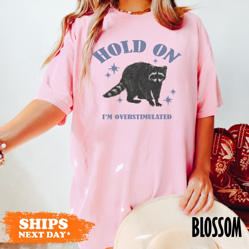 a woman wearing a pink shirt with a raccoon on it