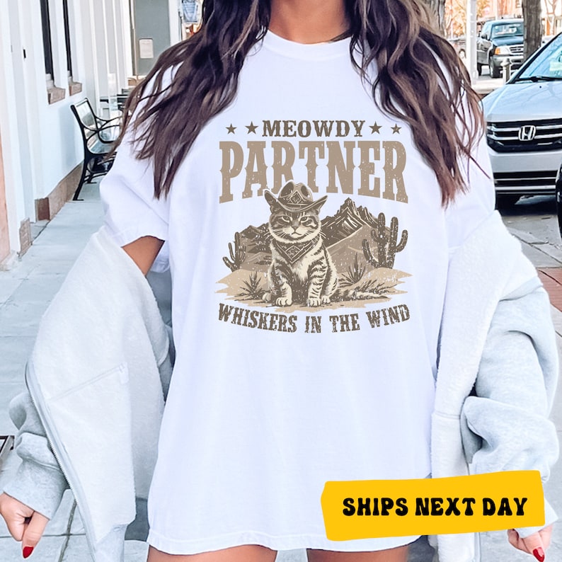 a woman wearing a white t - shirt with an image of a cat on it