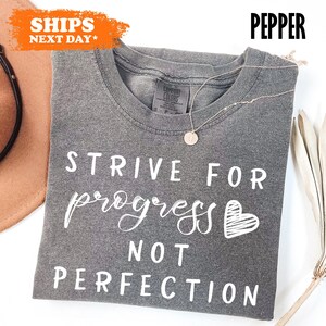a t - shirt that says strike for progress not perfection