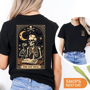 Peut inclure: T-shirt noir avec un motif d&eacute;taill&eacute; d'un v&eacute;t&eacute;rinaire squelette portant un st&eacute;thoscope et un bonnet d'infirmi&egrave;re, avec un chien squelette. Le motif comprend un croissant de lune, des chauves-souris et le texte "THE VET TECH".