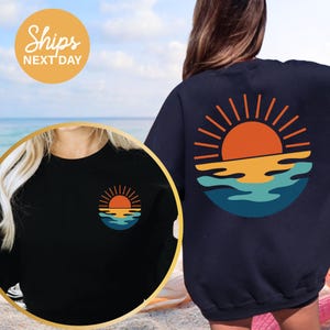 a woman wearing a sweatshirt with a sunset on it