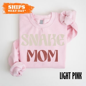 a pink shirt with the words snake mom on it