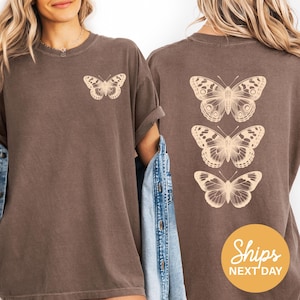 two women wearing brown t-shirts with white butterfly designs on the back.
