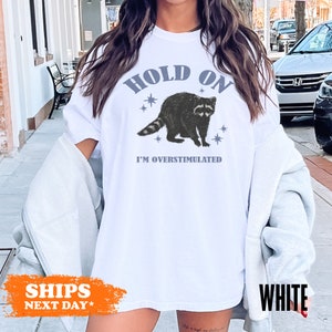 a woman wearing a white shirt with a raccoon on it