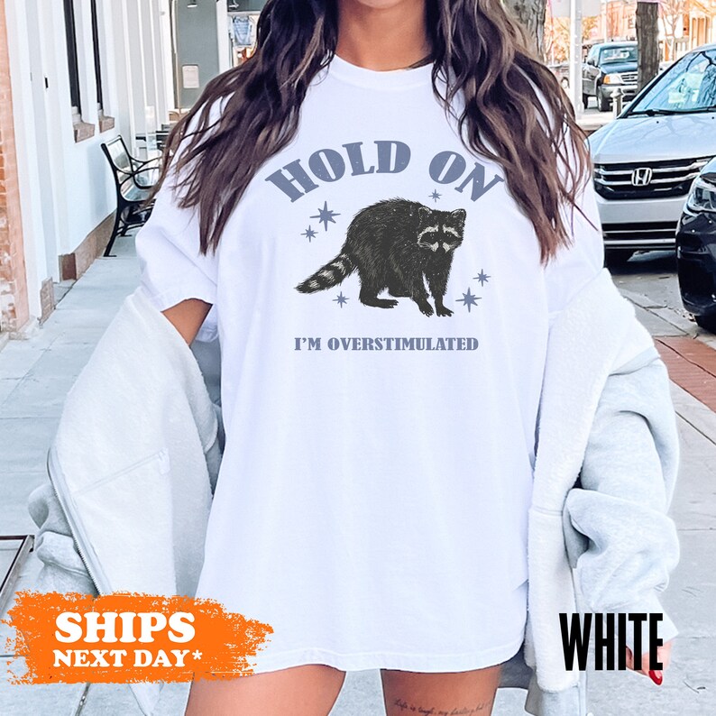 a woman wearing a white shirt with a raccoon on it