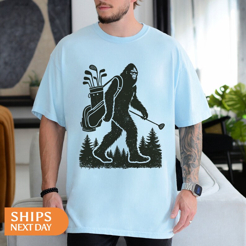 a man wearing a t - shirt with a bigfoot carrying a canoe