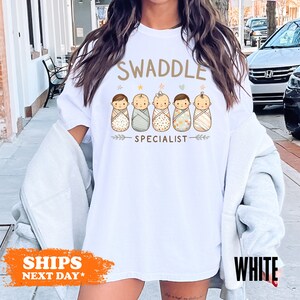 a woman wearing a swaddle special t - shirt