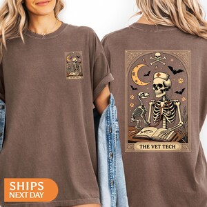 Peut inclure: T-shirt marron avec un motif de squelette v&eacute;t&eacute;rinaire, comprenant un chien squelette, un st&eacute;thoscope et le texte "THE VET TECH". Le motif comprend un croissant de lune, des chauves-souris et des empreintes de pattes.