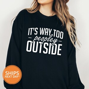 a woman wearing a black sweatshirt that says it's way too people outside