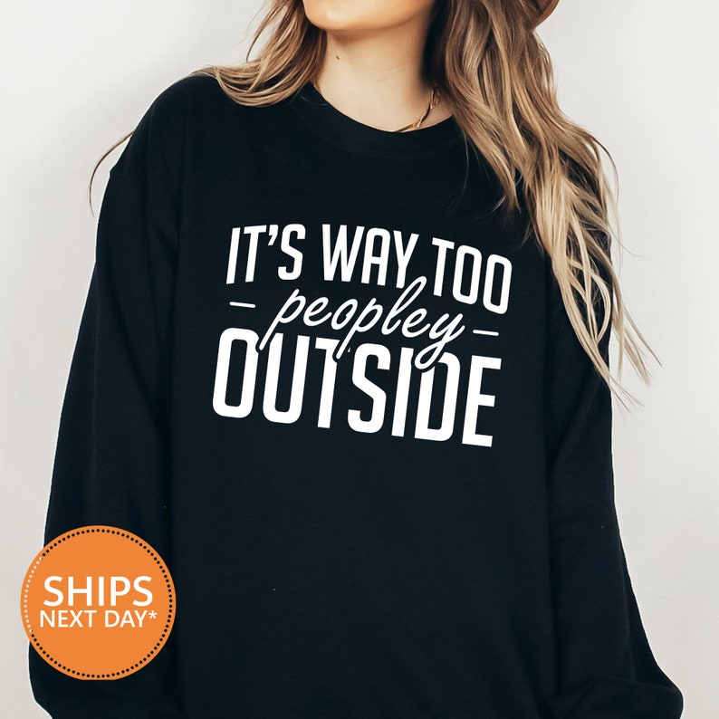 a woman wearing a black sweatshirt that says it's way too people outside