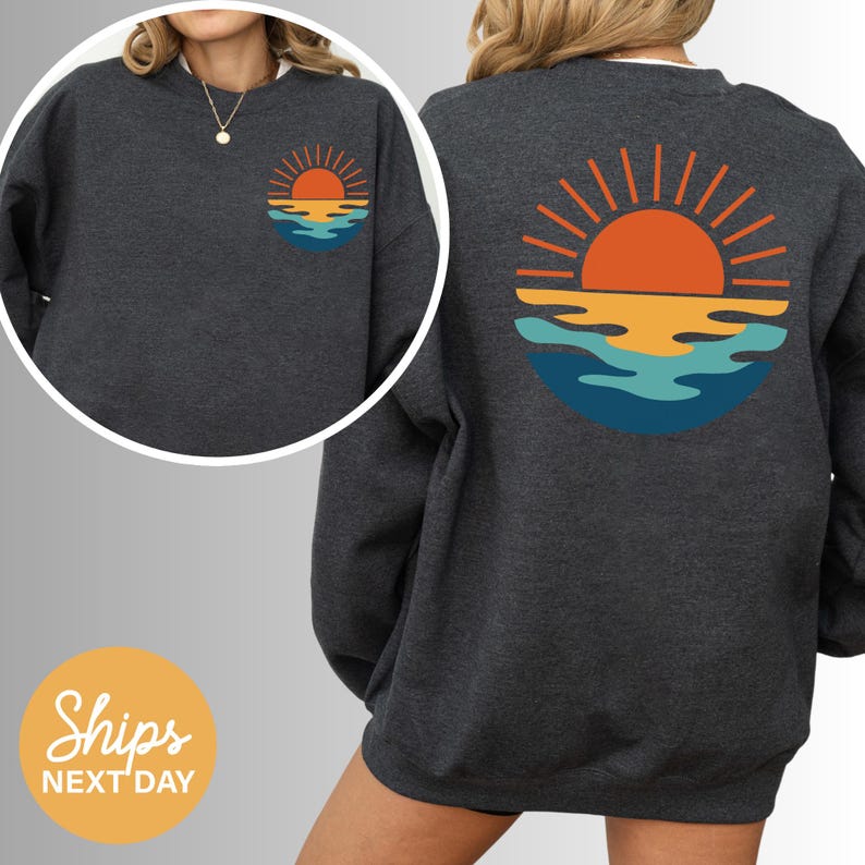 a woman wearing a sweatshirt with a sunset on it