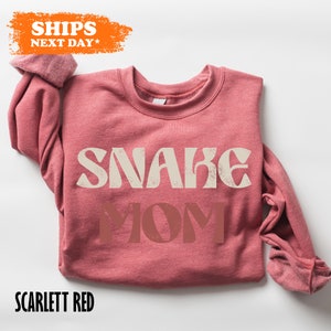 a pink sweater with the words snake mom on it