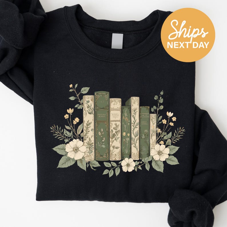 A black sweatshirt with a graphic design of a row of books surrounded by flowers and leaves.