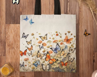 May include: A white canvas tote bag with black handles features a colourful watercolour design of butterflies on a floral background. The bag has the text "Pino's Parlor" printed on the top right corner.