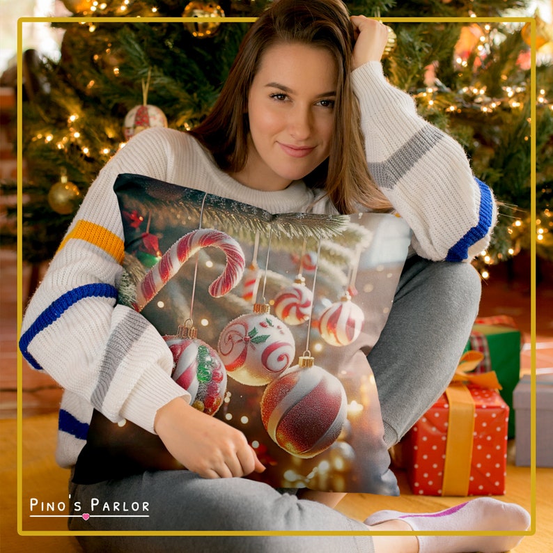 K&ouml;nnte beinhalten: Ein dekoratives Kissen mit einem Weihnachtsbaumdesign mit roten und wei&szlig;en Zuckerstangen, Kugeln und Lichtern. Das Kissen liegt auf einem Sofa, auf dem eine Person sitzt.