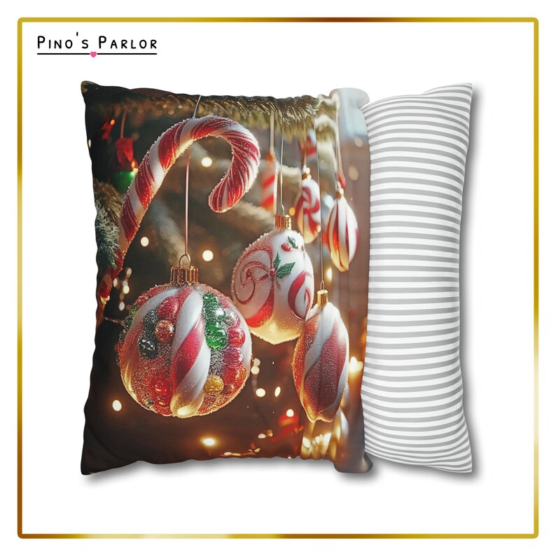 K&ouml;nnte beinhalten: Ein Weihnachts-Wurfkissen mit einem roten und wei&szlig;en Zuckerstangen und roten, wei&szlig;en und gr&uuml;nen Kugeln, die an einem Weihnachtsbaum h&auml;ngen. Das Kissen hat eine wei&szlig;e und graue gestreifte R&uuml;ckseite.