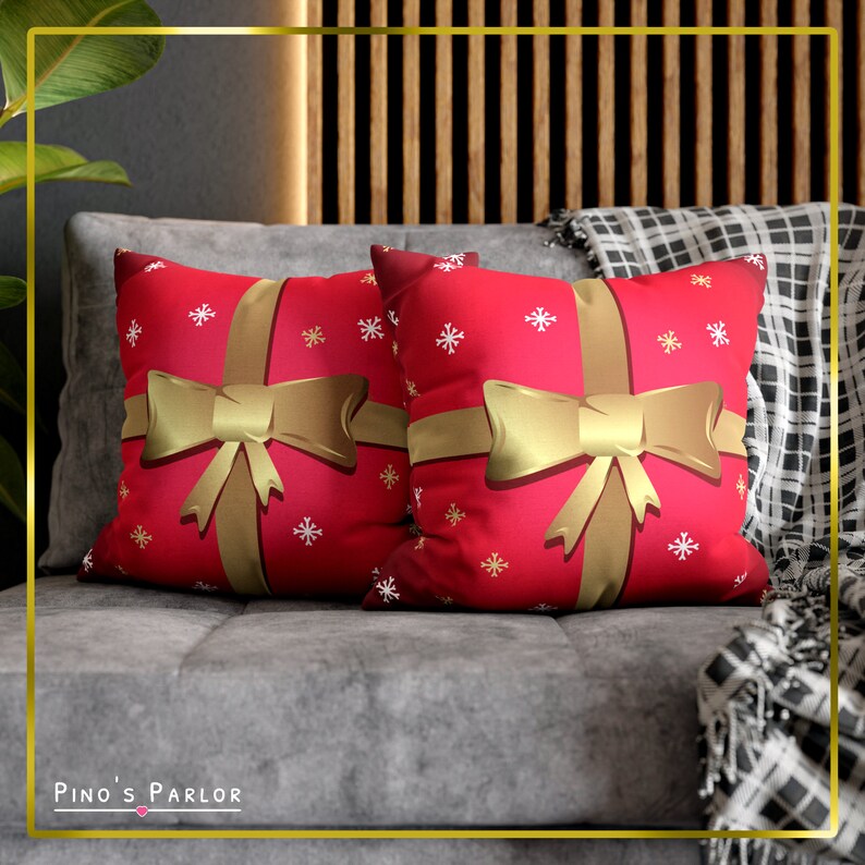 May include: Two red throw pillows with a gold ribbon and bow design. The pillows have a white snowflake pattern on a red background.