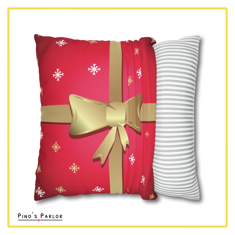 May include: Two decorative throw pillows. One pillow is red with a gold bow and white snowflakes. The other pillow is white with gray stripes. "Pino's Parlor" is printed on the bottom of the image.