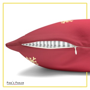 May include: A red throw pillow with a zipper closure and a subtle snowflake pattern in yellow. The pillow is made of a soft, plush fabric.
