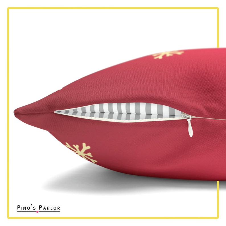 May include: A red throw pillow with a zipper closure and a subtle snowflake pattern in yellow. The pillow is made of a soft, plush fabric.