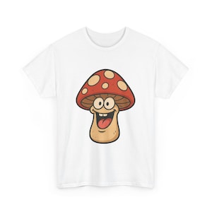 Könnte beinhalten: Weißes T-Shirt mit einem Cartoon-Pilz-Design. Der Pilz hat eine rote Kappe mit weißen Punkten, ein lächelndes Gesicht und eine herausragende Zunge. Das Design ist mittig auf dem T-Shirt platziert.