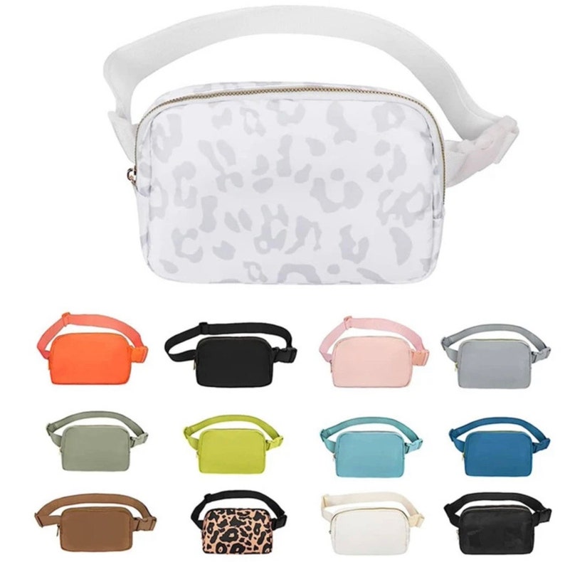 May include: A collection of 12 fanny packs in various colors and patterns, including leopard print, solid colors, and a white fanny pack with a leopard print design.