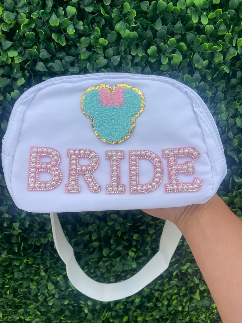 May include: White bridal clutch bag with a pearl-embellished "BRIDE" inscription and a turquoise and pink Minnie Mouse appliqu&eacute;.