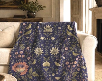 May include: A dark blue throw blanket featuring a repeating pattern of light-coloured birds, large blooming flowers, and intricate leafy vines. The design includes soft pink and cream floral accents set against a deep navy blue background.