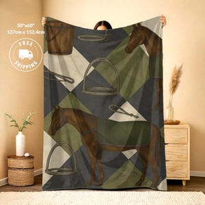 May include: A soft throw blanket measuring 50 inches by 60 inches, featuring a repeating pattern of brown horses, wooden buckets, and metal stirrups against a background of dark gray and olive green diamonds. The design includes equestrian gear.