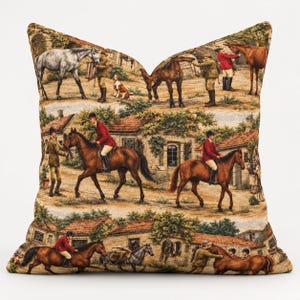 May include: A square throw pillow featuring a woven tapestry design of an equestrian scene. The pattern depicts multiple horses, riders in red and green jackets, and dogs in a rural setting with stone buildings and terracotta roofs.