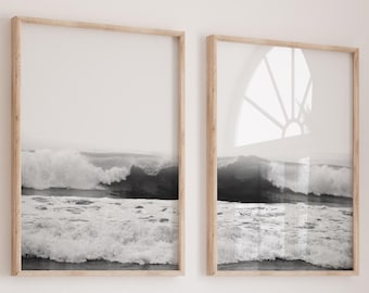 Può includere: Due stampe incorniciate in bianco e nero di onde oceaniche. Le immagini catturano il movimento delle onde con una cornice in legno chiaro. Le stampe sono esposte su una parete bianca, creando un'estetica minimalista.