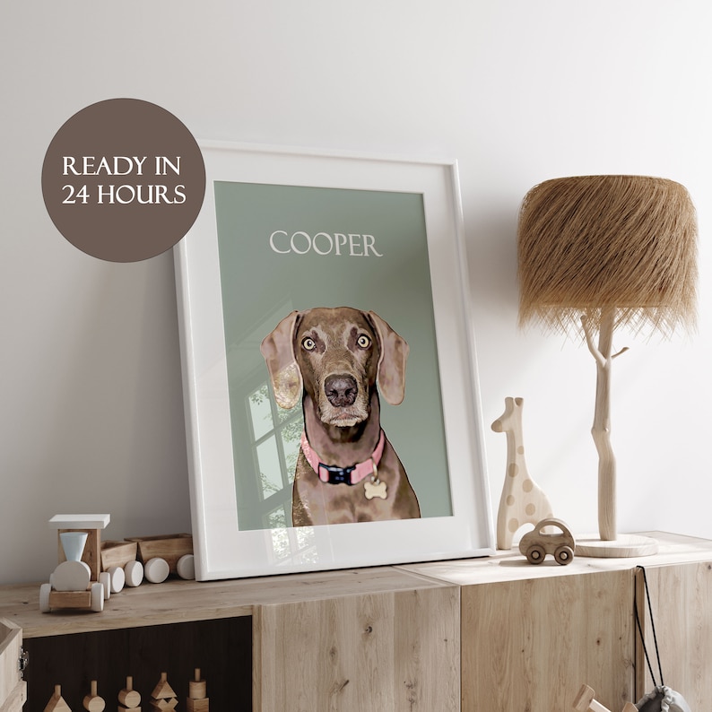 Op de afbeelding: Een witte ingelijste print met een lichtgroene achtergrond waarop een bruine hond met een roze halsband te zien is. De naam van de hond "COOPER" staat in wit bovenaan de print.