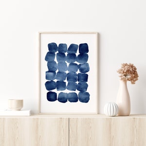 Puede incluir: Una impresi&oacute;n enmarcada de una pintura abstracta de acuarela con un esquema de color azul y blanco. La pintura presenta una serie de c&iacute;rculos superpuestos en tonos de azul, creando un patr&oacute;n texturizado y org&aacute;nico.