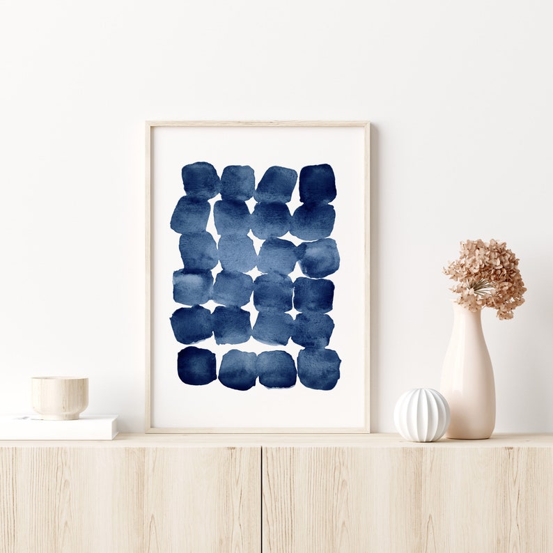 Puede incluir: Una impresi&oacute;n enmarcada de una pintura abstracta de acuarela con un esquema de color azul y blanco. La pintura presenta una serie de c&iacute;rculos superpuestos en tonos de azul, creando un patr&oacute;n texturizado y org&aacute;nico.