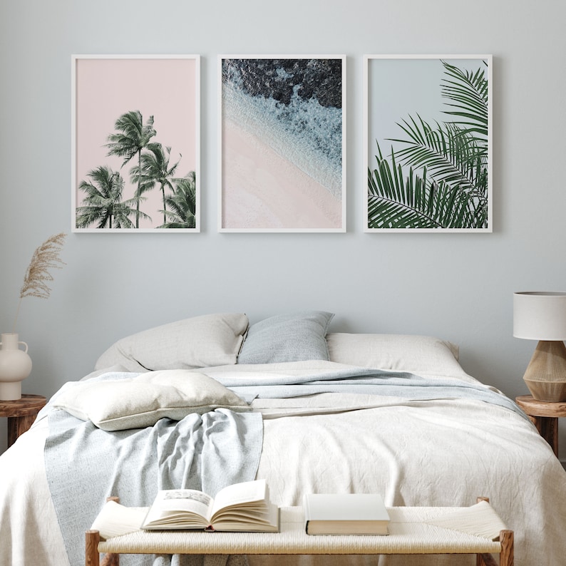 Puede incluir: Tres impresiones enmarcadas con un tema tropical. La primera impresi&oacute;n presenta un fondo rosa con tres palmeras. La segunda impresi&oacute;n muestra una escena de playa con agua azul y arena blanca. La tercera impresi&oacute;n muestra un primer plano de una hoja de palmera.