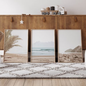 May include: Three framed beach scene prints with a wooden frame and white matting. The prints are hung on a wooden wall unit with a toy truck on top.