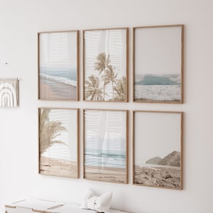 May include: A set of six framed prints featuring beach scenes with palm trees, waves, and sandy shores. The prints are in a light wood frame and are arranged in a grid pattern on a white wall.