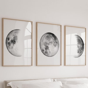 Pode incluir: Três impressões em preto e branco emolduradas da lua em diferentes fases. As impressões estão em molduras de madeira simples e estão penduradas em uma parede branca.