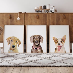 Op de afbeelding: Drie ingelijste prints van hondenportretten. De prints zijn in witte lijsten en tonen een Labrador Retriever, een Weimaraner en een Corgi.