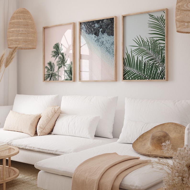 Puede incluir: Un sof&aacute; blanco con tres almohadas y una manta. Tres impresiones enmarcadas de escenas tropicales cuelgan en la pared detr&aacute;s del sof&aacute;. Las impresiones muestran palmeras, olas del oc&eacute;ano y una playa tropical.
