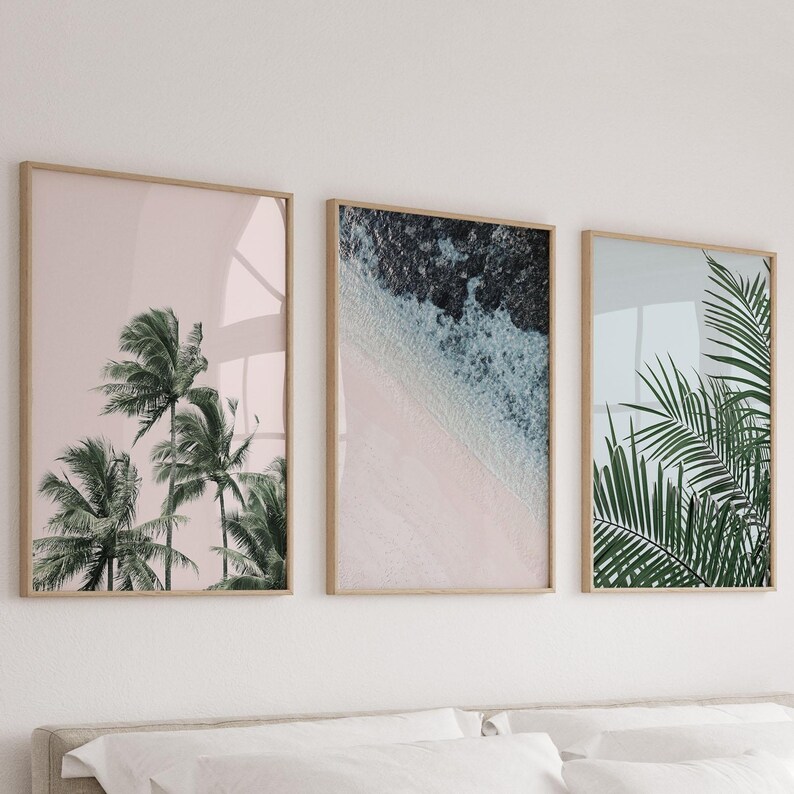 Puede incluir: Tres impresiones enmarcadas con un tema tropical. La primera impresi&oacute;n presenta un fondo rosa con palmeras. La segunda impresi&oacute;n presenta una escena de playa azul y blanca. La tercera impresi&oacute;n presenta una hoja de palmera verde.
