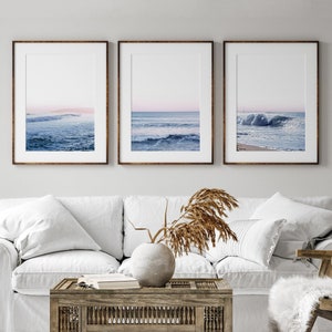 May include: Three framed art prints featuring ocean wave photography. Each print has a brown frame and a white mat. The ocean scenes depict waves in shades of blue and white, with a hint of pink in the sky.