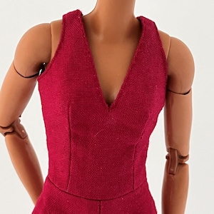 Może przedstawiać: Głęboko czerwony kombinezon bez rękaw&oacute;w z dekoltem w kształcie litery V. Tkanina ma teksturowany wygląd, a odzież jest dopasowana za pomocą szw&oacute;w, kt&oacute;re definiują gorset. Kombinezon jest prezentowany na manekinie.